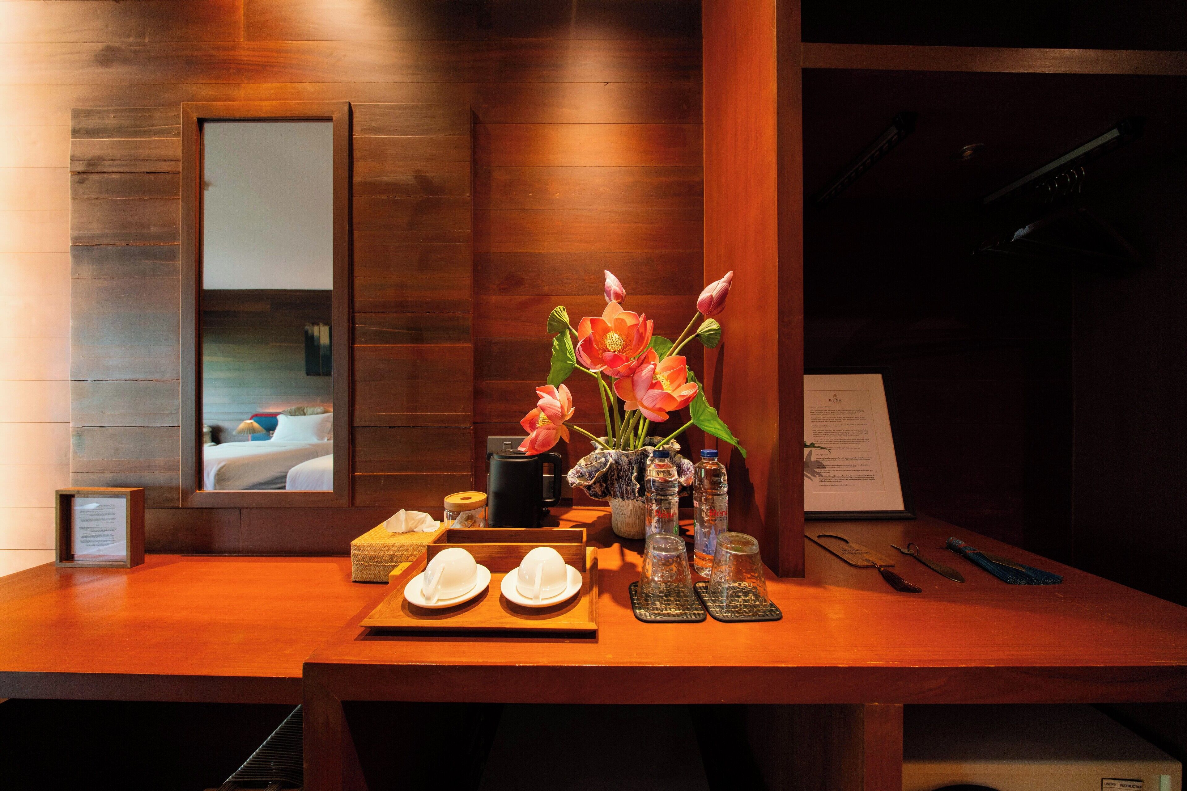 Una scrivania di legno per la reception con un vaso di fiori rosa, un quadro incorniciato e un menu.