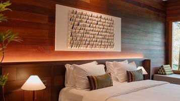 A bedroom with a large bed, wooden panel walls, a woven side table, and a wall-mounted artwork.