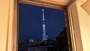 A view of the Tokyo Tower at night through a window, with buildings in the foreground. - Stay Work Asakusa Guesthouse (Tokyo)