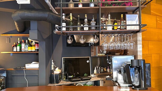 A bar area with shelves of liquor bottles, wine glasses, and a coffee machine. - Stay Work Asakusa Guesthouse (Tokyo)