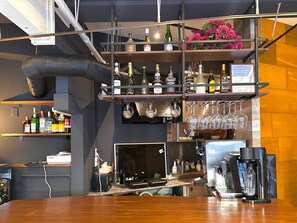 A bar area with shelves of liquor bottles, wine glasses, and a coffee machine. - Stay Work Asakusa Guesthouse (Tokyo)
