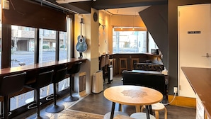 A cafe with a bar area, a seating area with tables and chairs, and a staff room. - Stay Work Asakusa Guesthouse (Tokyo)