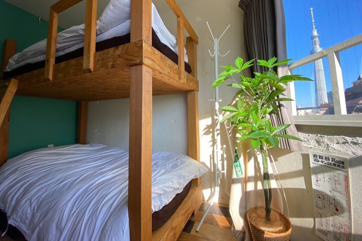 Ein Mehrbettzimmer mit Blick auf einen Turm durch ein Fenster.
