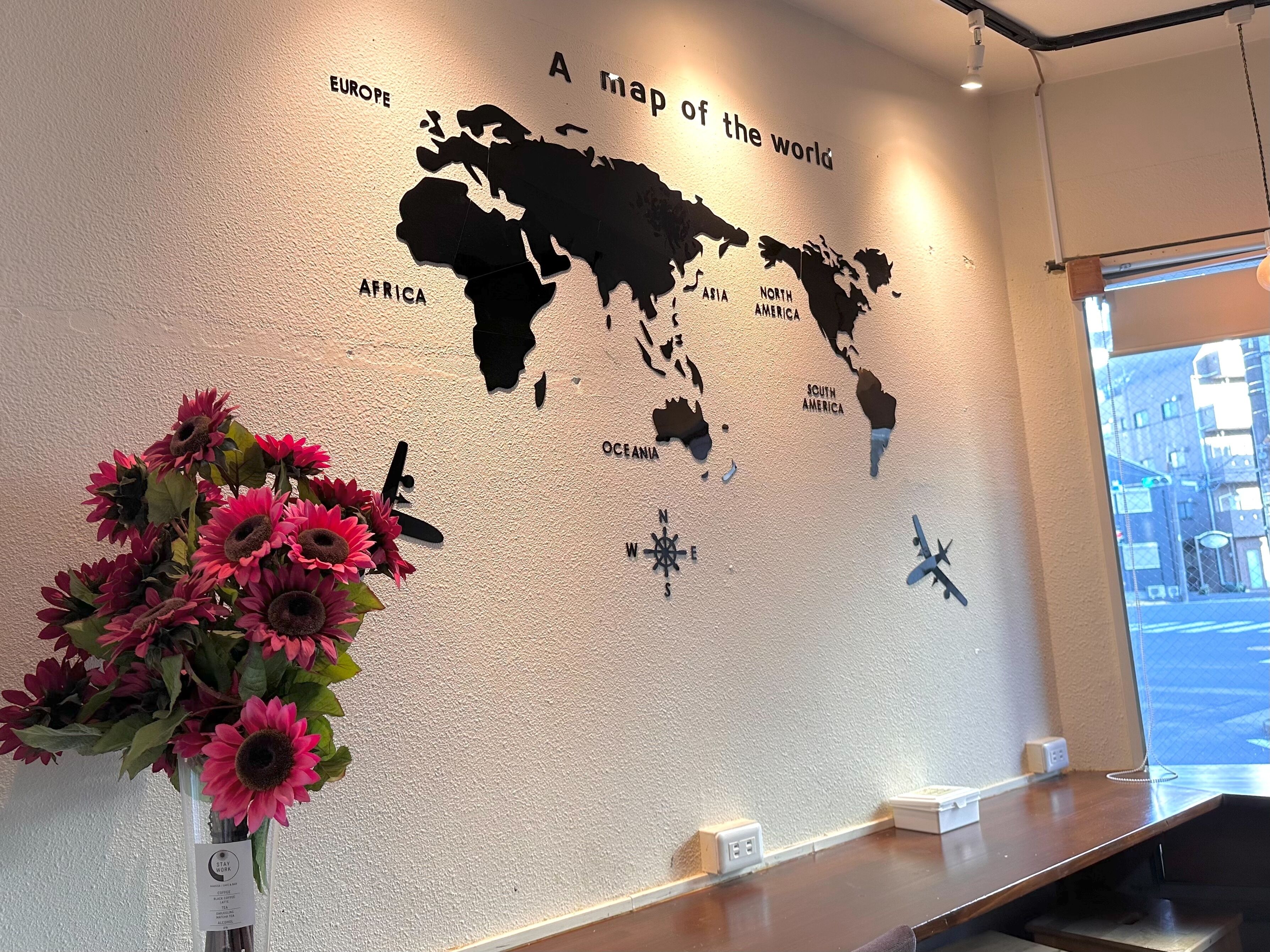 A world map on a wall with a window view.