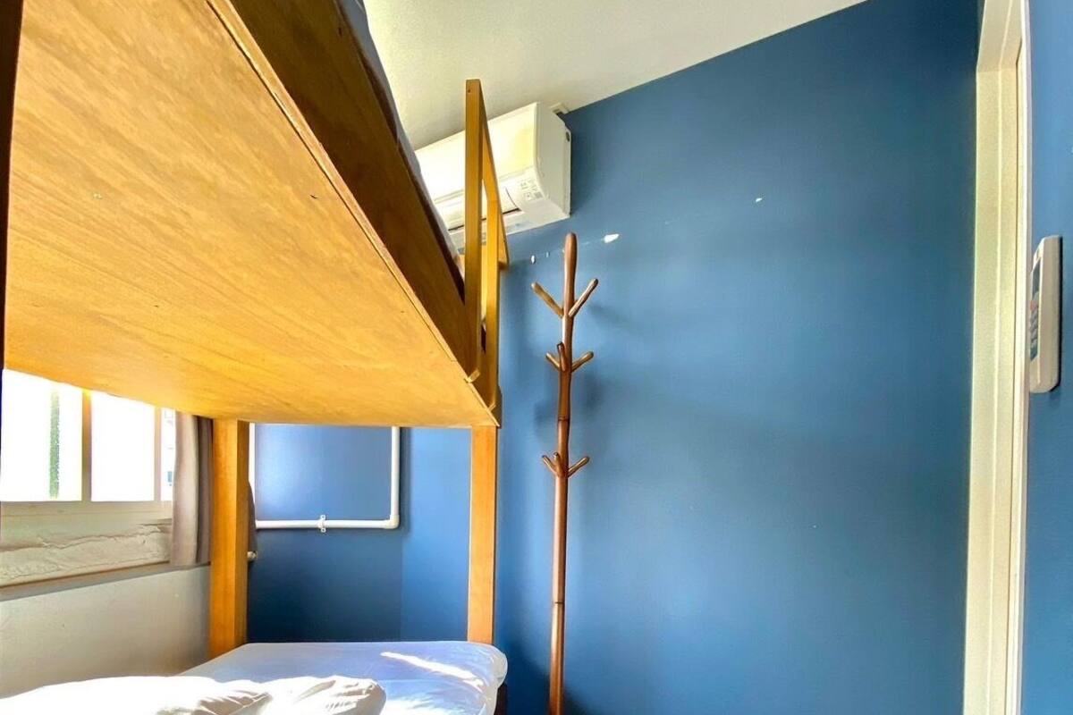 Ein Schlafraum mit Etagenbetten, Holzboden und einem Fenster, inklusive Kleiderhaken.