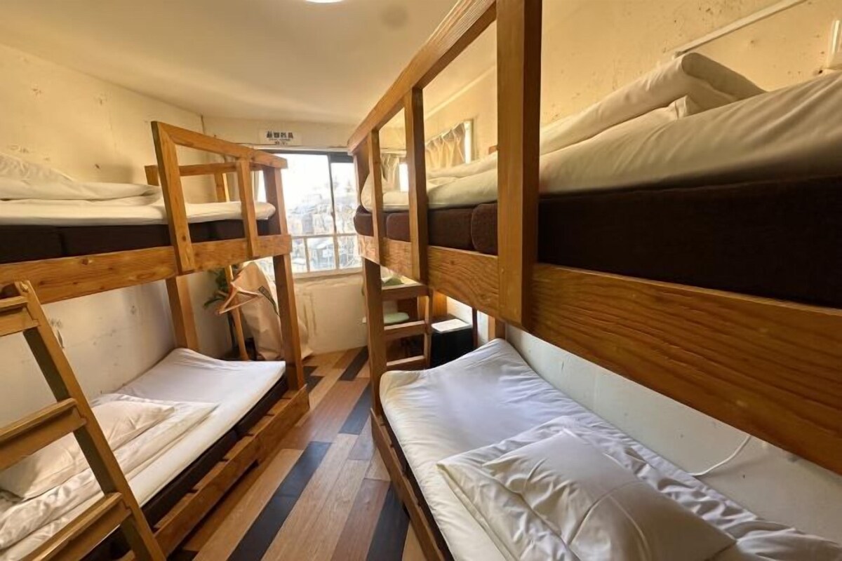 A dormitory room with bunk beds, a window, and a radiator.