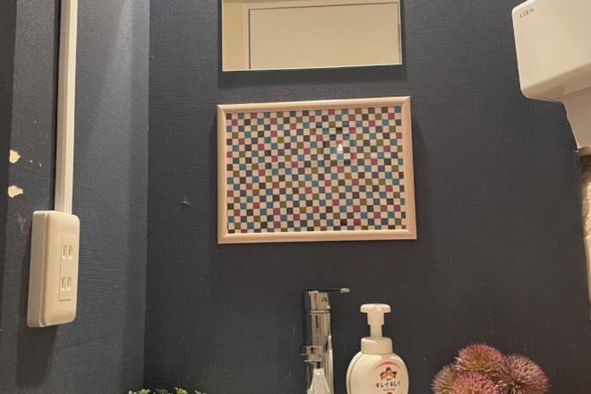 A bathroom with a checkered wall art, a hand dryer, and a soap dispenser.