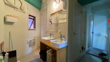 A bathroom with two sinks, a mirror, a fan, and a window.