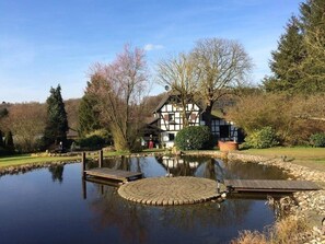A traditional half-timbered house with a pond and wooden docks. - Historic half-timbered house from the 18th century, listed building (Hennef)