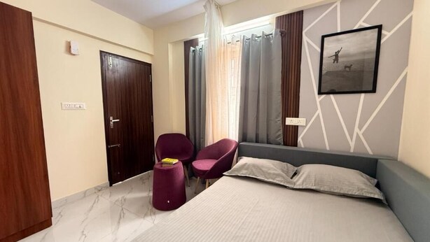 Una habitación de hotel con cama, una silla, un escritorio y una ventana con cortinas.