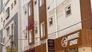 Un edificio de varios pisos con un letrero que dice 'Live', un letrero 'Mobile Spot' y varios scooters estacionados.