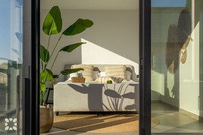 Ein modernes Schlafzimmer mit Sofa, Kissen, einer Pflanze und einem Fenster mit Aussicht.
