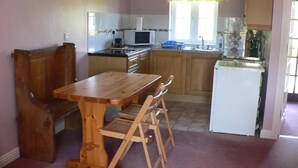 Une cuisine avec des meubles de rangement en bois, une table à manger et un réfrigérateur.