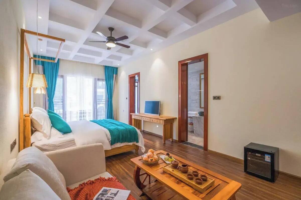 A hotel room with a bed, a desk, a television, a heater, and a window with curtains.