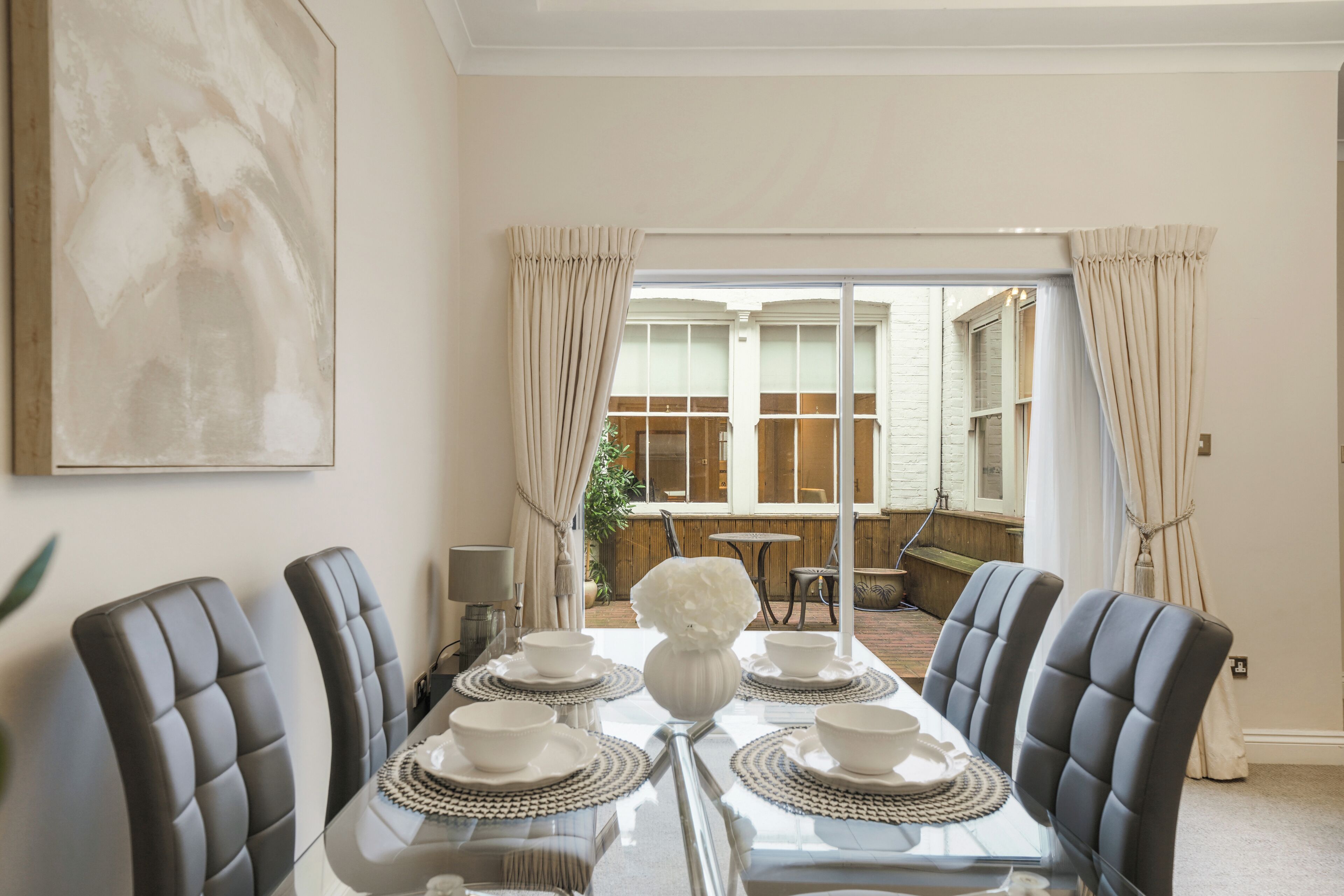 Ein Essbereich mit einem Glastisch, weißen Tellern und schwarzen Stühlen.
