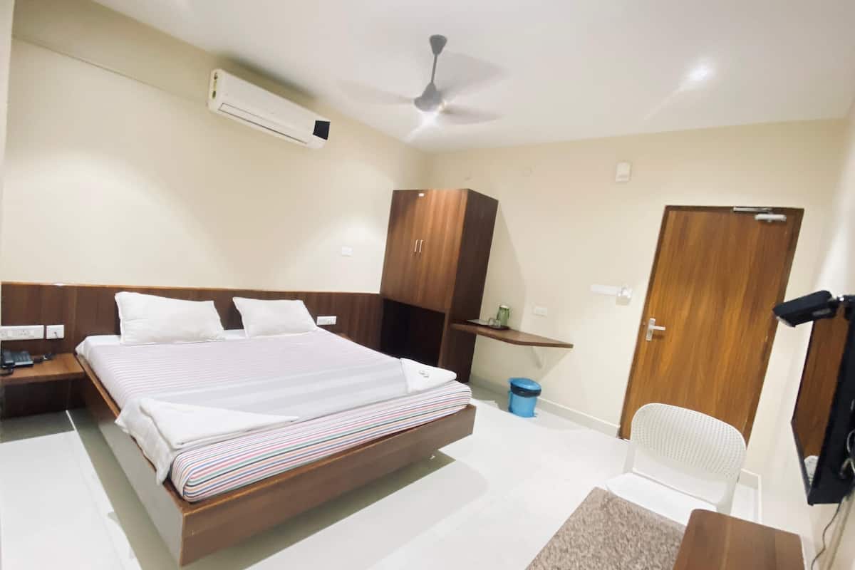 Hotelkamer met een groot bed, een bureau, een stoel, een kledingkast, een plafondventilator en een airconditioning.