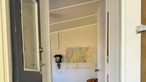 Una puerta que da a una habitación con piso de madera, una silla, un mapa en la pared y una pequeña mesa.
