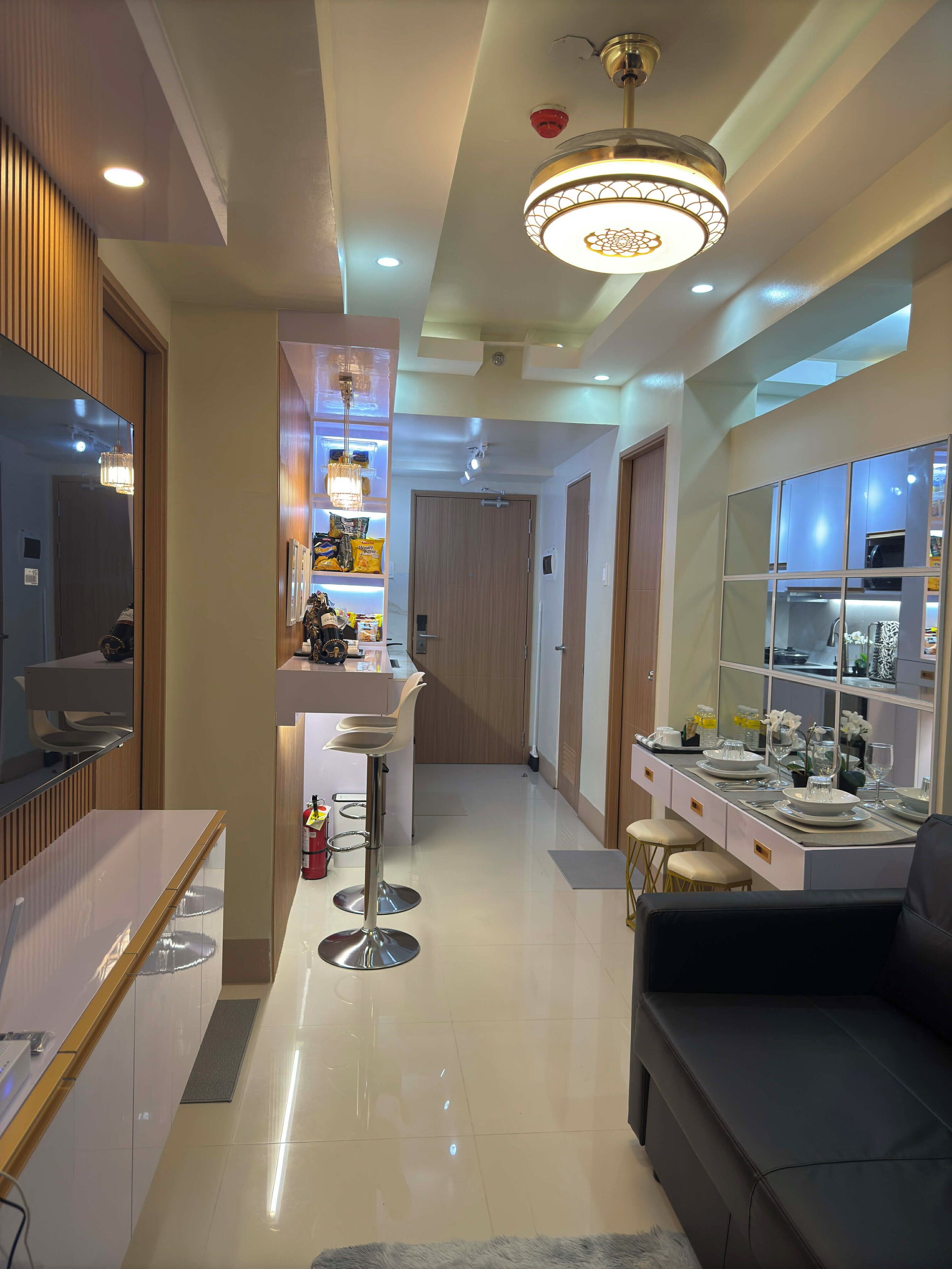 A modern kitchen with a central island, a dining area with a sofa, and a bar area with stools.