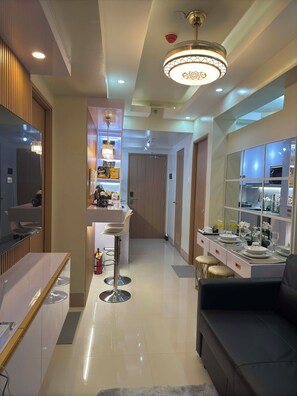 A modern kitchen with a central island, a dining area with a sofa, and a bar area with stools. - Ella’s Haven @ Shore 3 Residences • 2BR Walk to MOA • Minutes from NAIA (Pasay City)