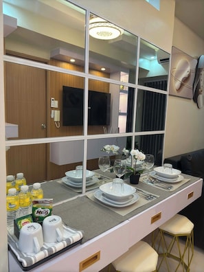 A modern dining area with a large mirror, a flat-screen TV, and a sofa. - Ella’s Haven @ Shore 3 Residences • 2BR Walk to MOA • Minutes from NAIA (Pasay City)