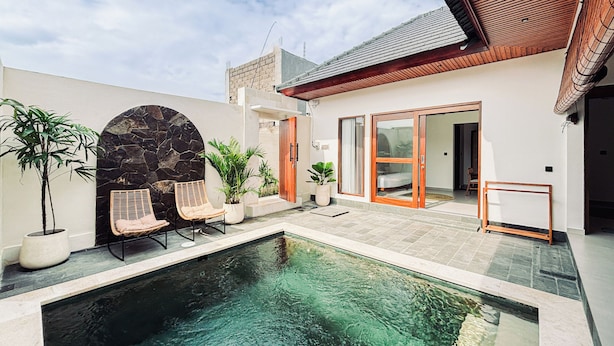 Una casa moderna con piscina, arco de piedra y puertas de madera.