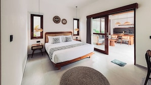 Un dormitorio moderno con una cama grande, una mesita de noche y vistas a la cocina por una puerta abierta.