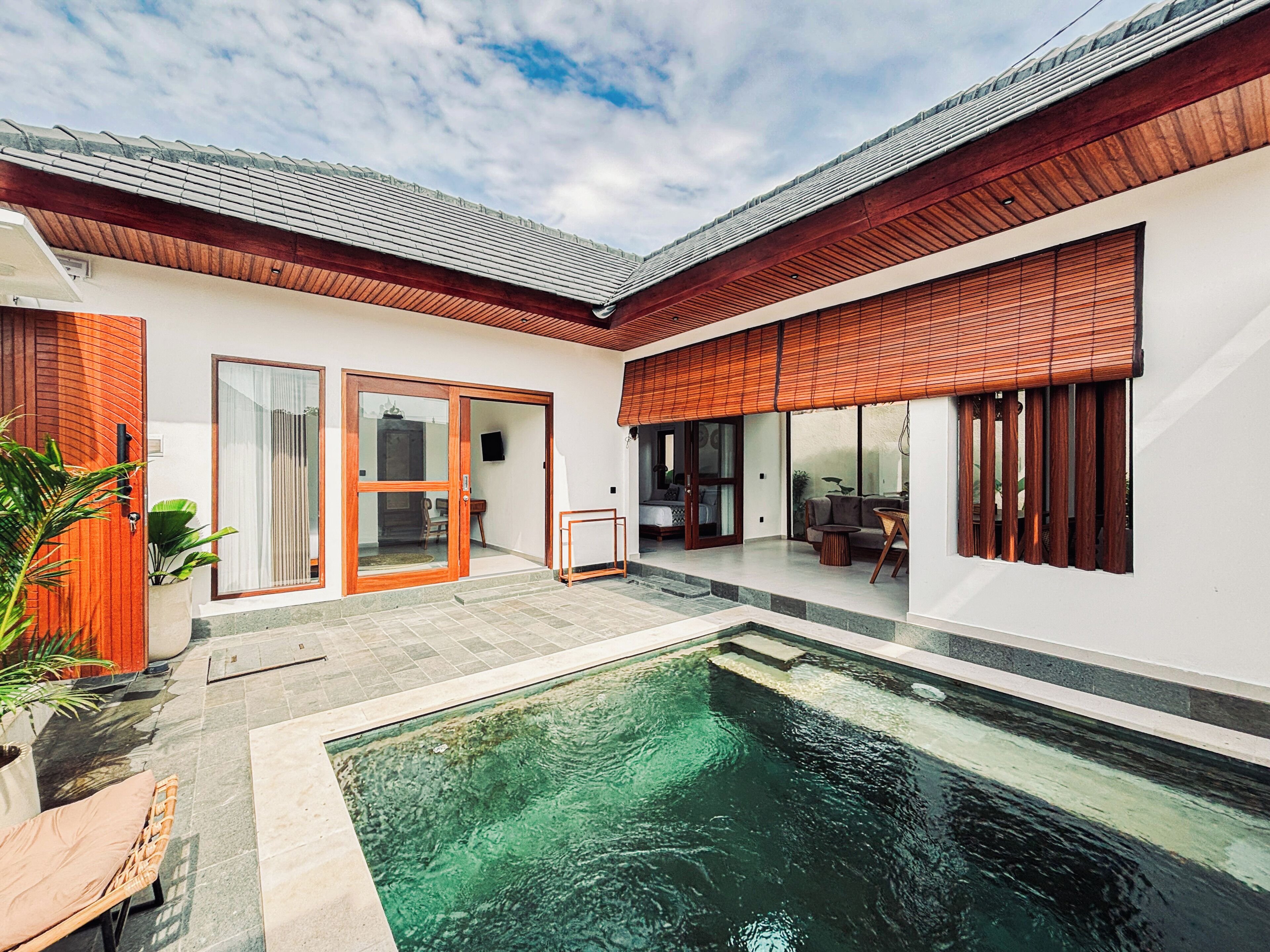 A modern house with a swimming pool, large glass doors, and wooden accents.