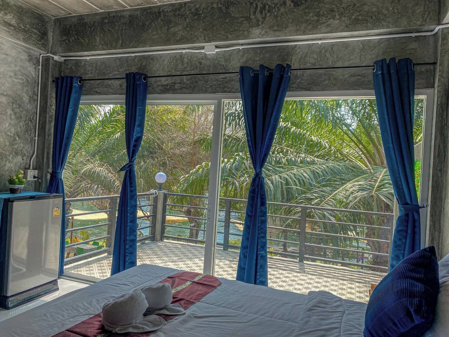 Ein Hotelzimmer mit Bett, Schreibtisch und Blick auf Pool und Palmen.