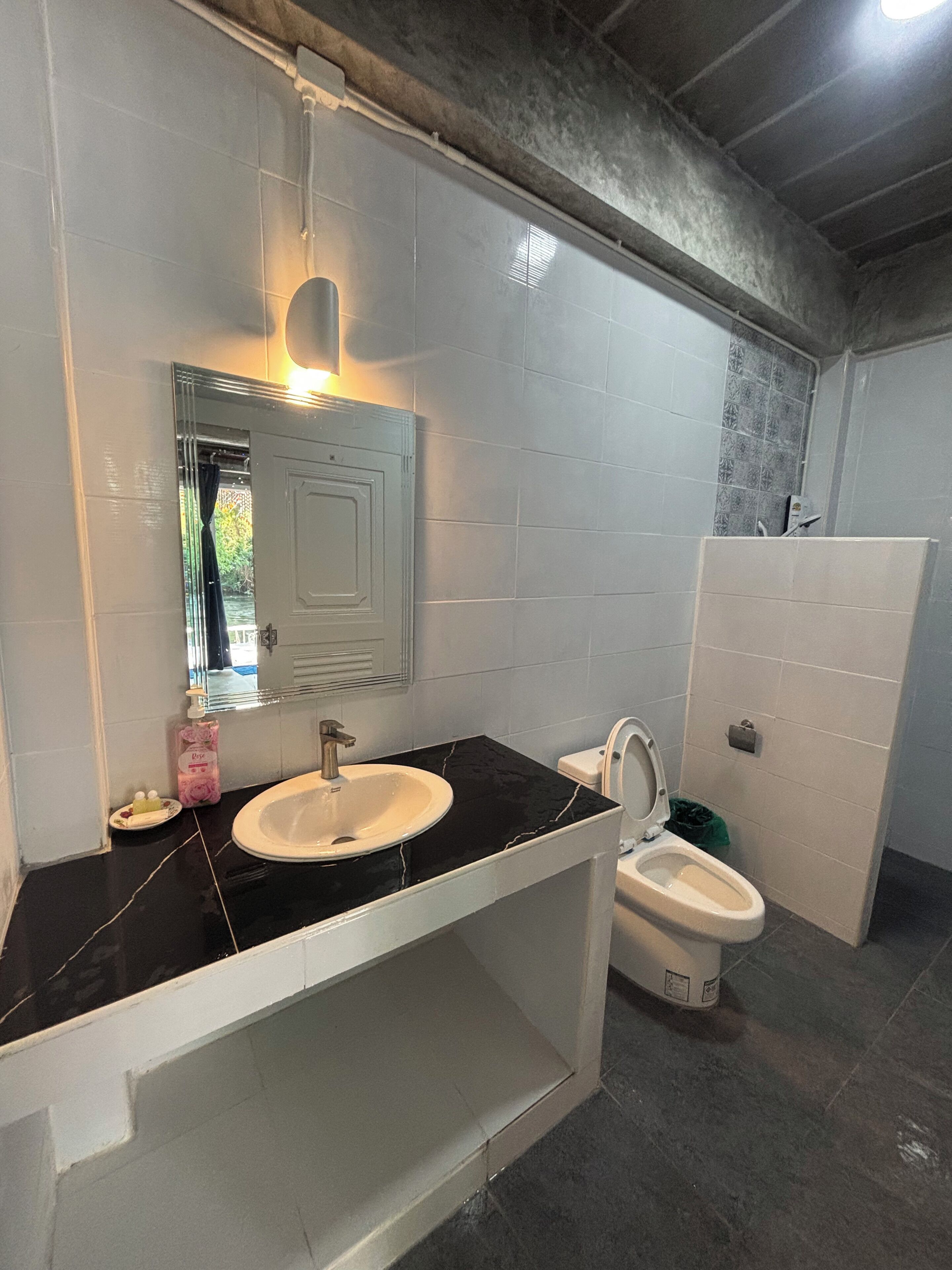 Un baño con lavamanos de encimera negra, inodoro blanco y tocador blanco.