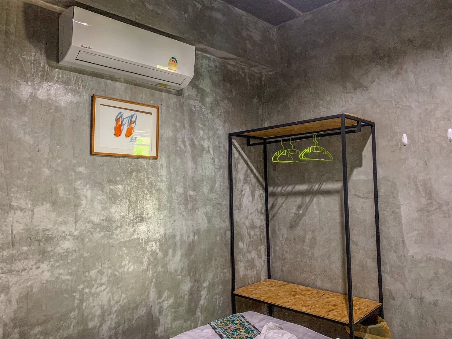 A room with a bunk bed, a framed picture on the wall, and a hanging shoe rack.