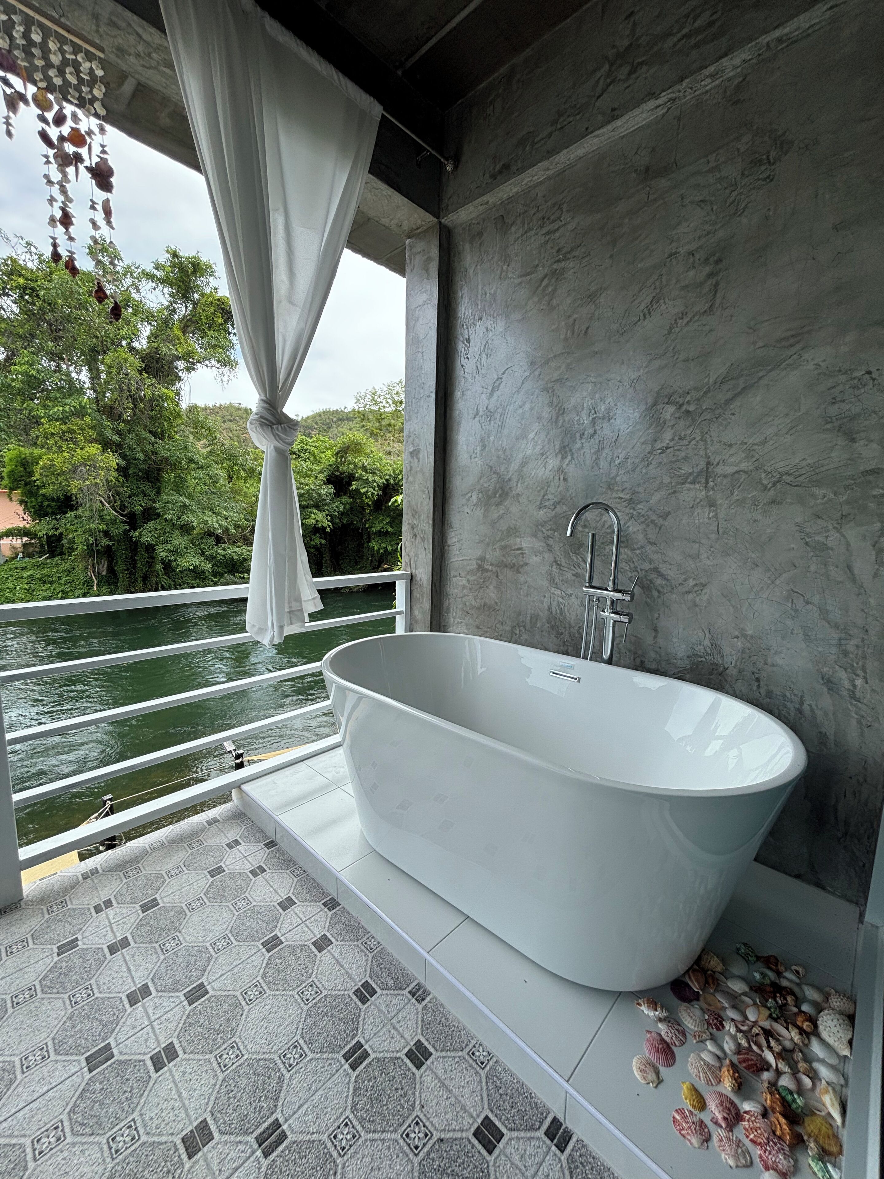 Une salle de bain moderne avec une baignoire sur pieds, une vue sur une rivière et un carrelage au motif original.