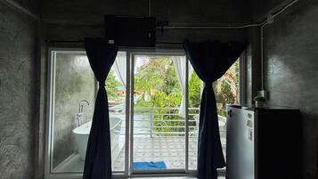 Baño con bañera, inodoro y lavamanos. Posee una puerta corrediza de vidrio que da a un área exterior con balcón.