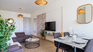 A modern living room with a sofa, coffee table, and dining area set. - Yellow Canvas 2-BR & Balcony in Larnaca (Larnaca)