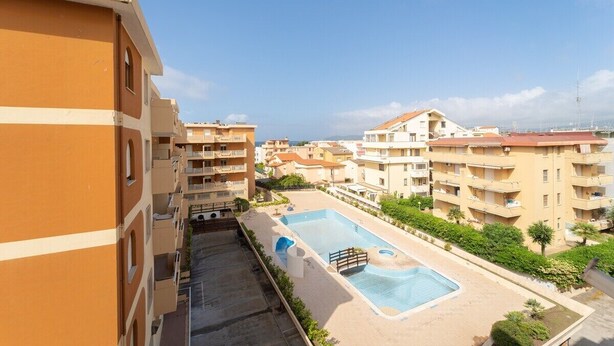 A residential building with a swimming pool, balconies, and a clear view of the surrounding area. - Summer seaview (Alghero)