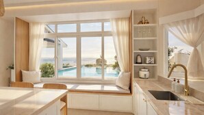 A modern kitchen with a view of a pool, a built-in bench, and a breakfast bar. - Alesea Baroro: Private Beachfront Villa - Pool, Jacuzzi (Bacnotan)