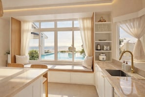 A modern kitchen with a view of a pool, a built-in bench, and a breakfast bar.