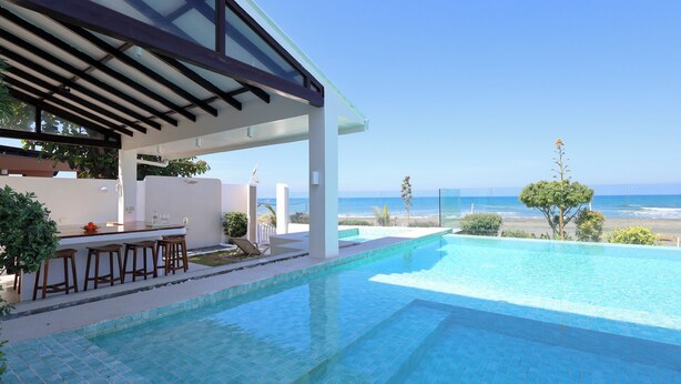 A pool with a bar area, a covered seating area, and a view of the ocean. - Alesea Baroro: Private Beachfront Villa - Pool, Jacuzzi (Bacnotan)