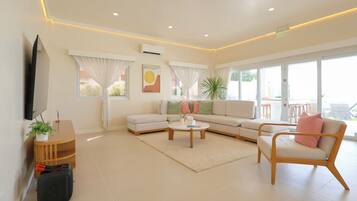 Una sala de estar moderna con un sofá, un sillón, una mesa de centro y una mesita auxiliar con una planta.
