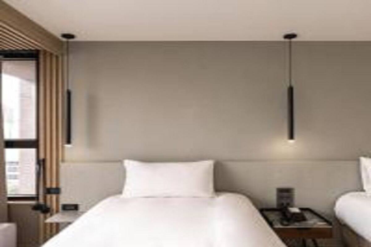 Ein modernes Hotelzimmer mit einem großen Bett, Nachttischen und einem Fenster mit Jalousien.