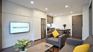 Una sala de estar moderna con un sofá gris, una mesa de centro y un televisor montado en la pared.