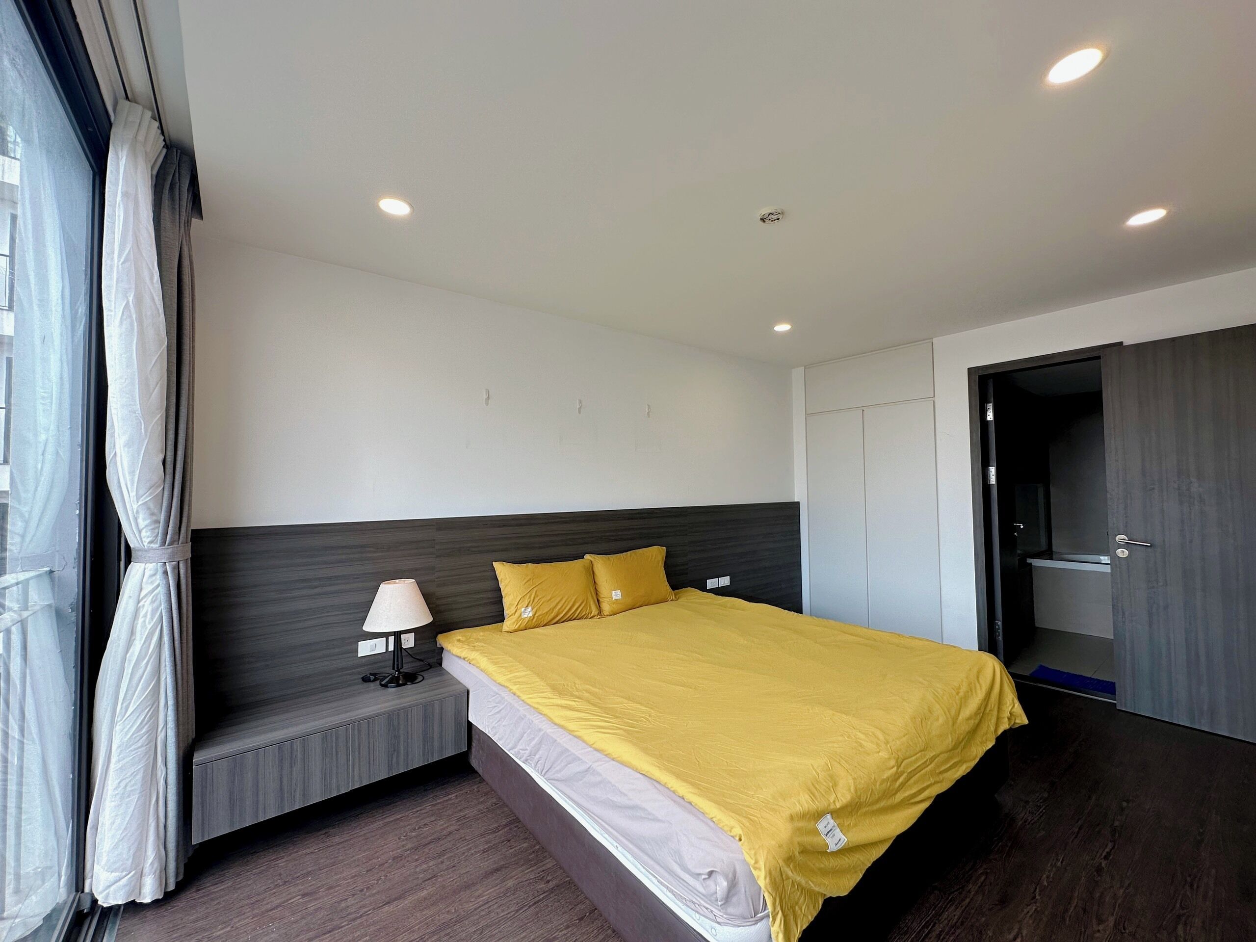 A modern bedroom with a bed, bedside lamp, and a wardrobe.
