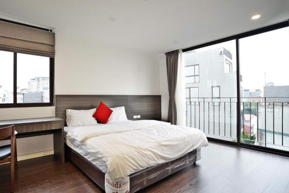 Une chambre d’hôtel moderne, dotée d’un grand lit, d’un bureau et offrant une vue sur la ville par la fenêtre.