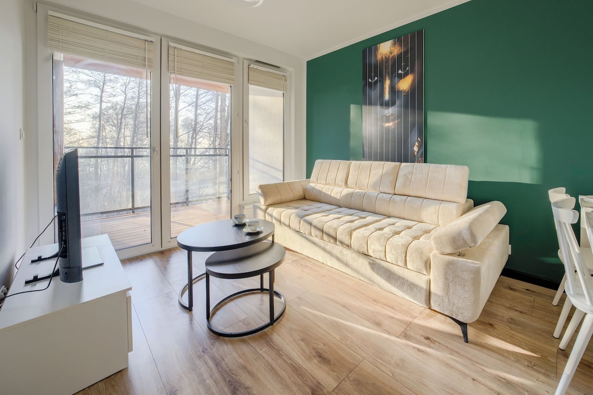 Una sala de estar moderna con un sofá color beige, una mesita redonda y un televisor de pantalla plana.