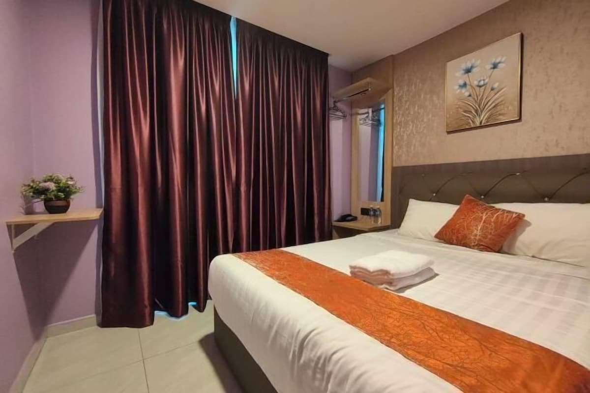 A hotel room with a bed, a nightstand, a mirror, and a window with curtains.