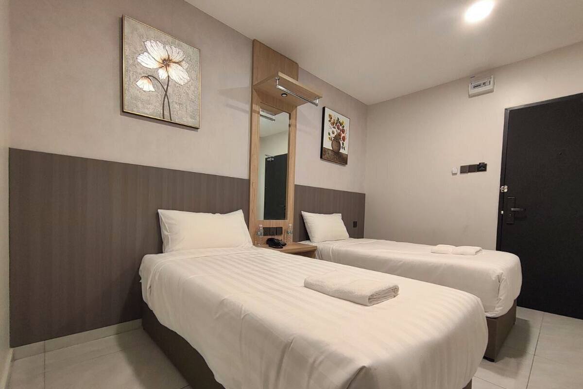 Habitació d'hotel amb dos llits, un mirall gran i obres d'art a les parets.