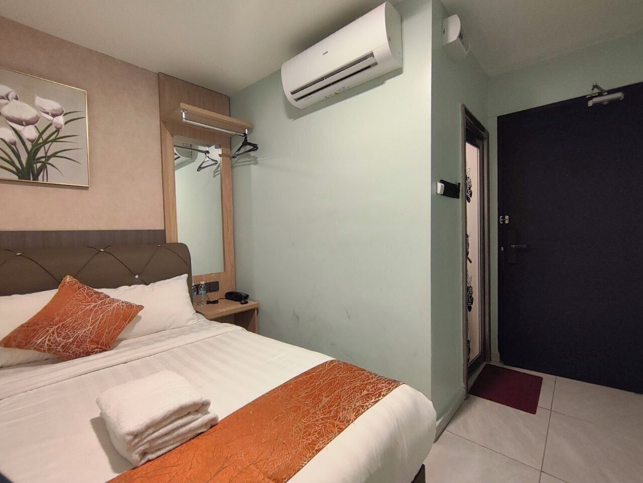 Habitación de hotel con una cama, aire acondicionado, una mesita de noche y un espejo.