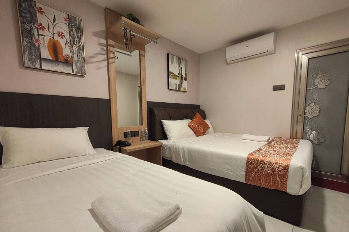 Habitació d'hotel amb dos llits, una tauleta de nit de fusta, un mirall i obra d'art a les parets.