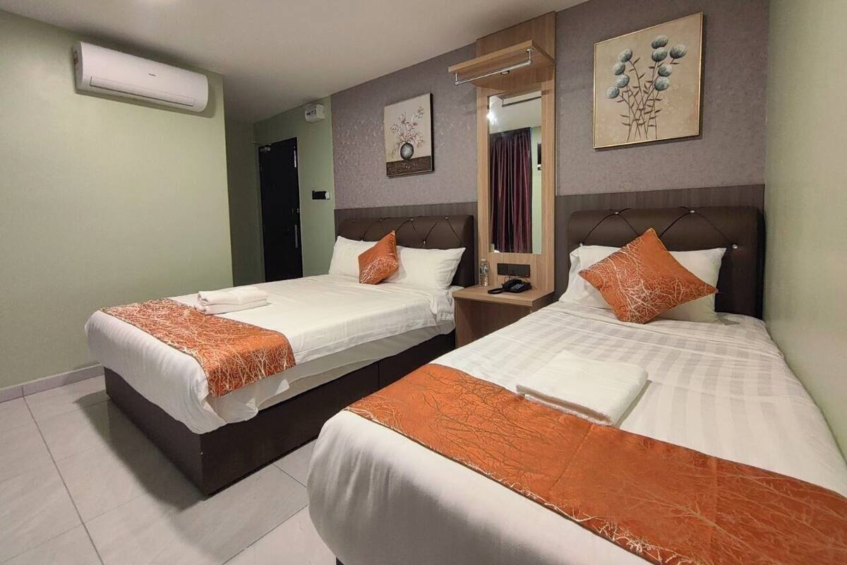 Habitació d'hotel amb dos llits, un mirall i obres d'art a les parets.