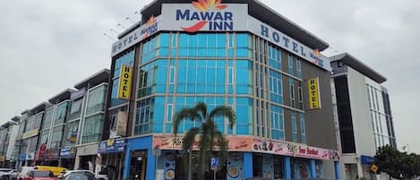 A Mewar Inn hotel with a modern facade, large windows, and a prominent sign.