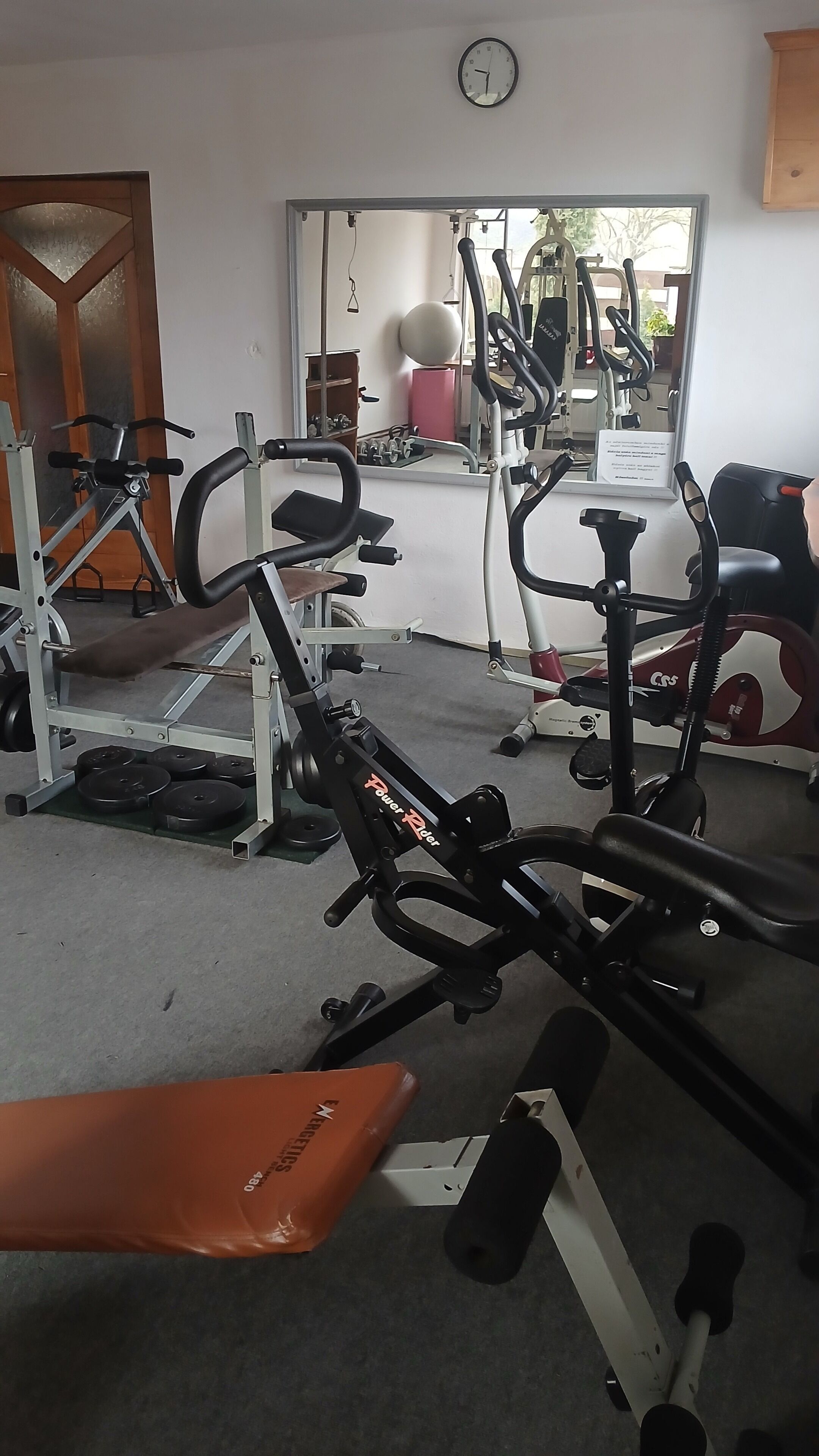 Une salle de sport équipée de divers appareils d’exercice, notamment un banc, des appareils de musculation et des appareils de cardio.